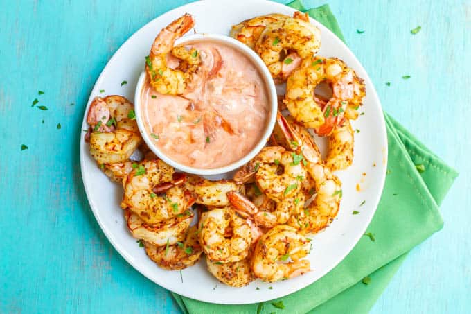 Cooked southwestern shrimp served on a white plate with a dipping sauce