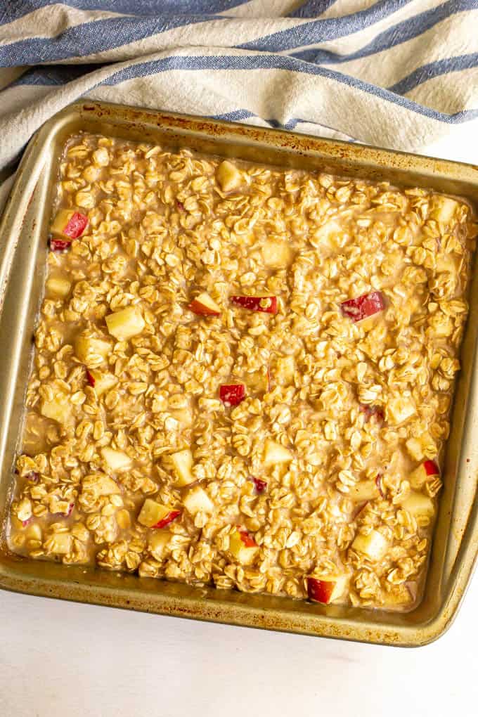 A oatmeal mixture with chunks of apple in an 8x8 pan before being cooked.