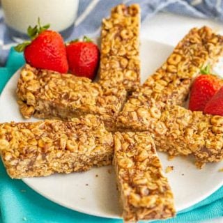 A plate of breakfast bars arranged in a burst pattern with strawberries alongside