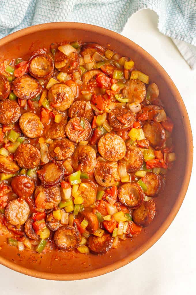 Cajun sausages mixed with tomatoes and veggies in a large skillet