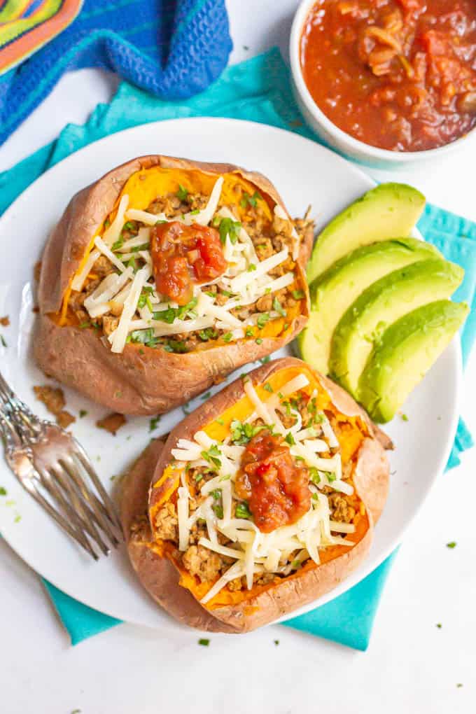 Overhead of sweet potatoes with ground turkey taco filling and cheese, cilantro and salsa on top