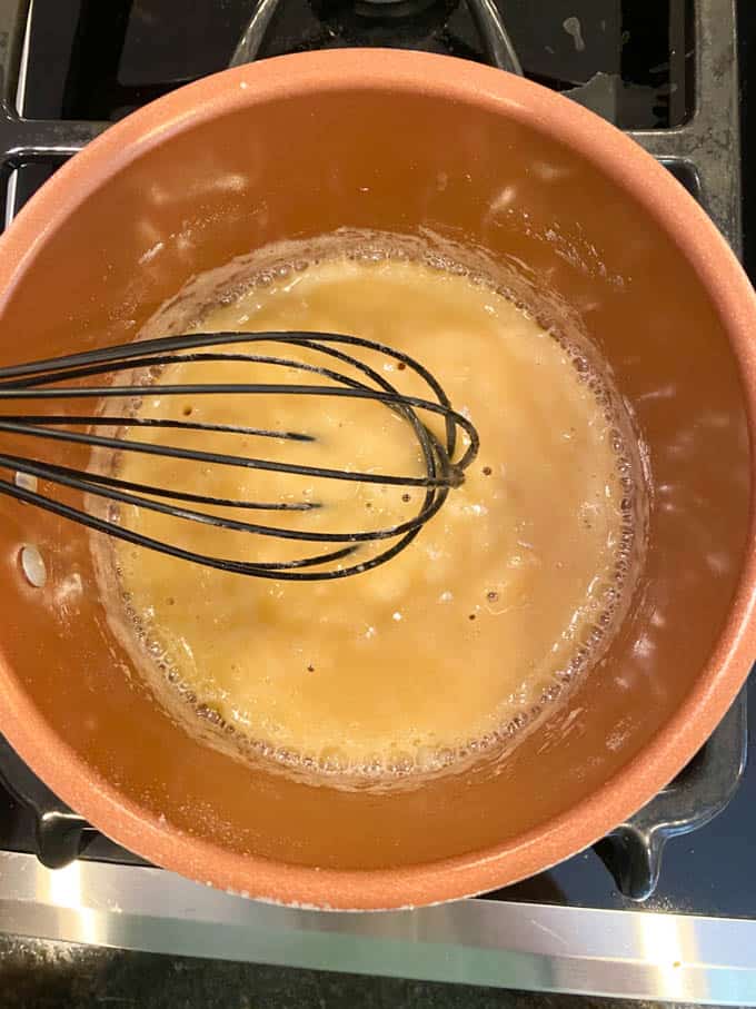 A whisk making a roux of butter and flour in a pan