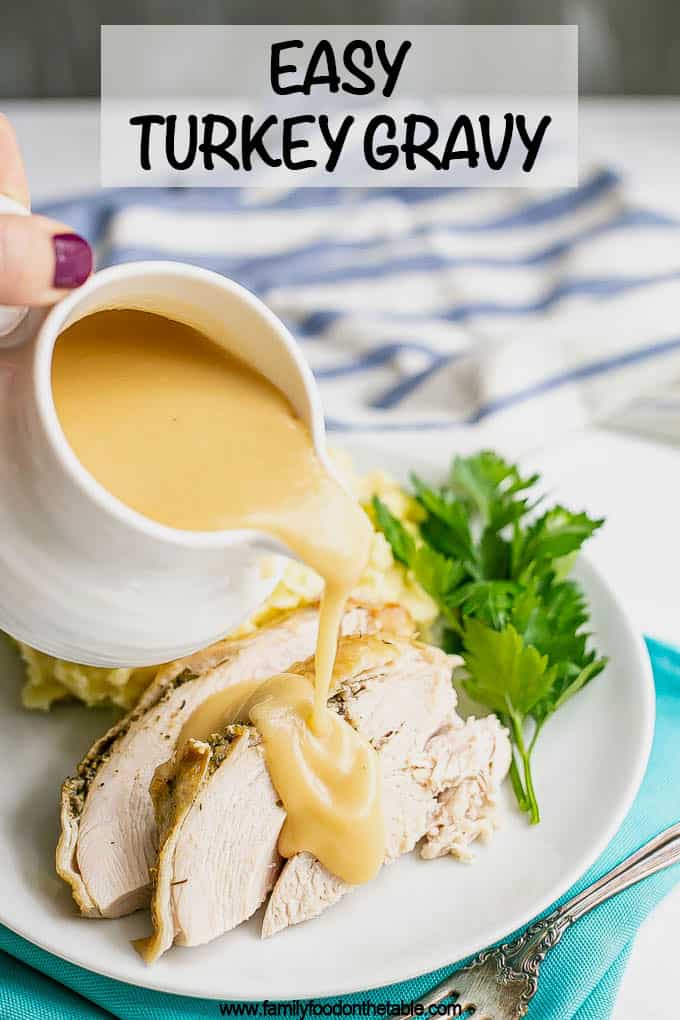 Gravy being poured over sliced turkey on a white dinner plate