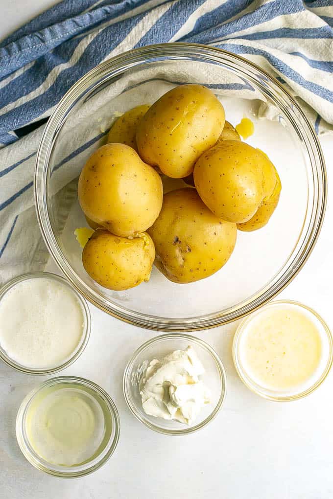 Ingredients for mashed potatoes laid out on a white marble counter