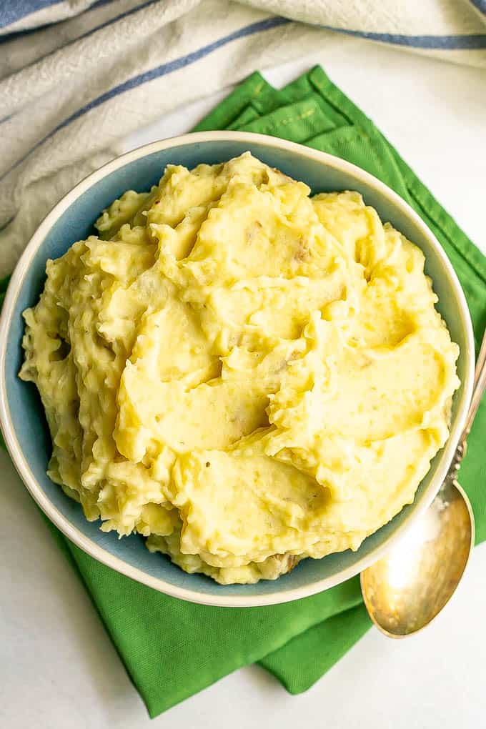 Creamy mashed potatoes served in a white and blue bowl on top of green napkins
