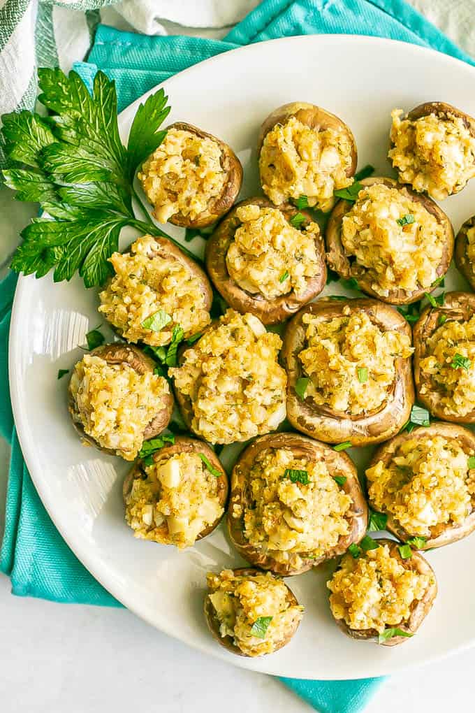 Close up overhead shot of a white serving plate full of stuffed mushrooms with a garnish of parsley