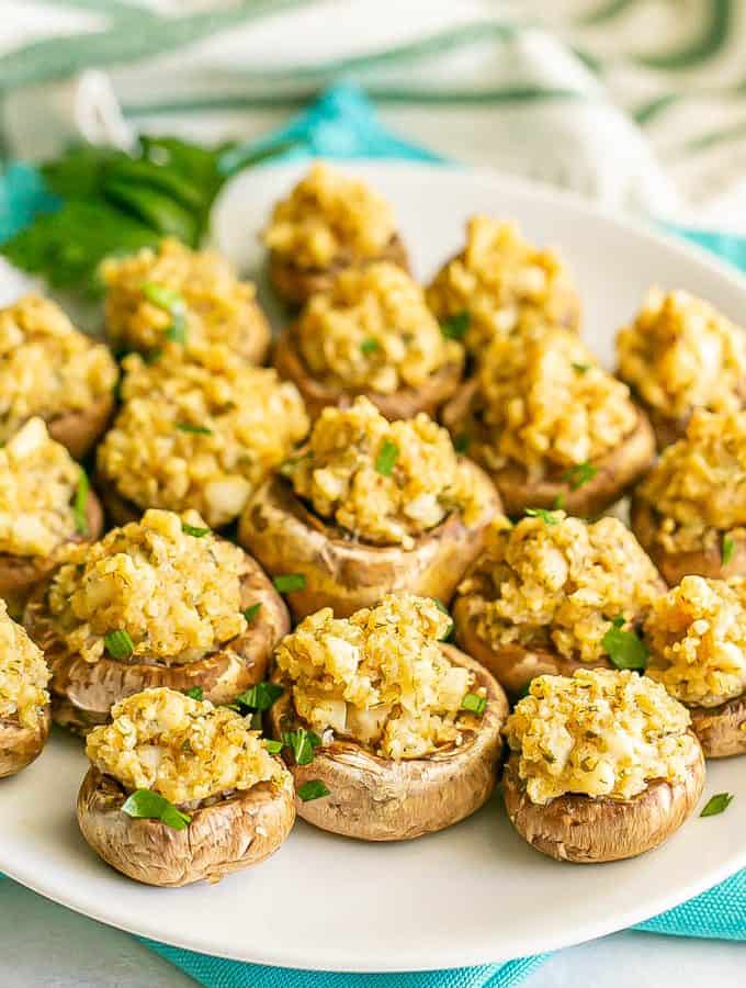 Browned baked stuffed mushrooms with breadcrumbs and Parmesan cheese served on a white plate