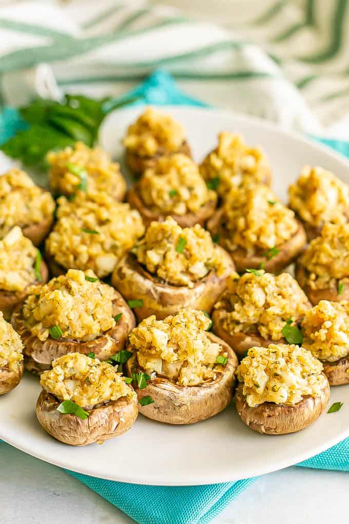 Browned baked stuffed mushrooms with breadcrumbs and Parmesan cheese served on a white plate