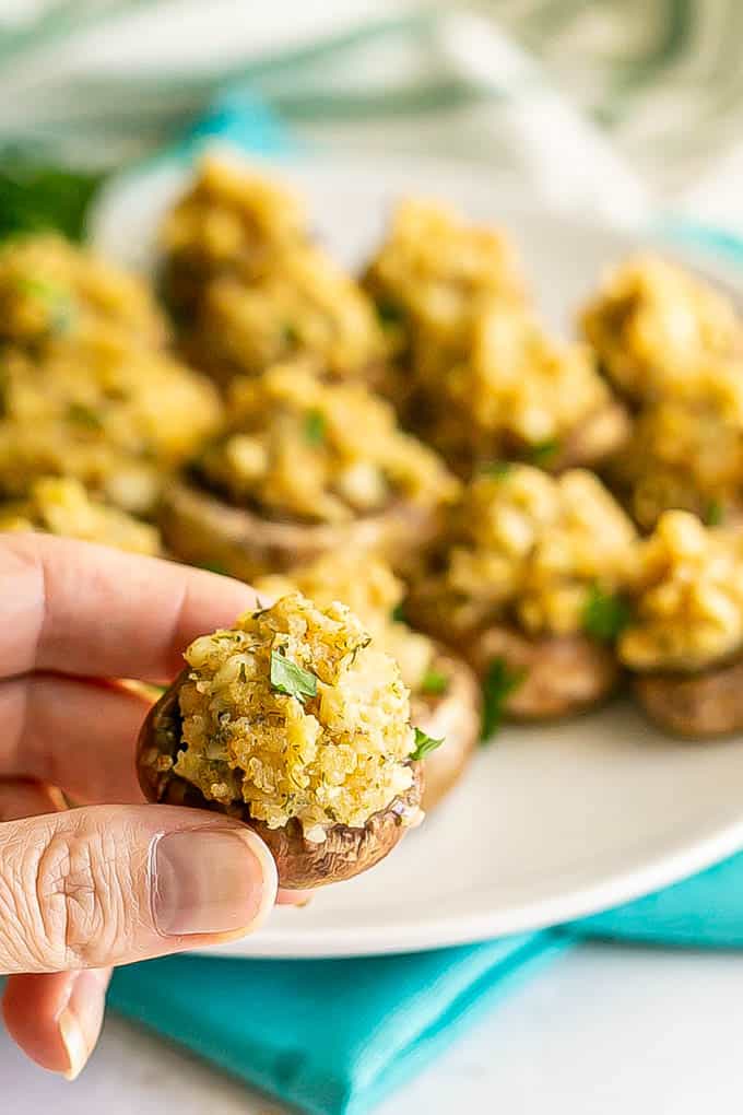 A hand picking up a stuffed mushroom appetizer