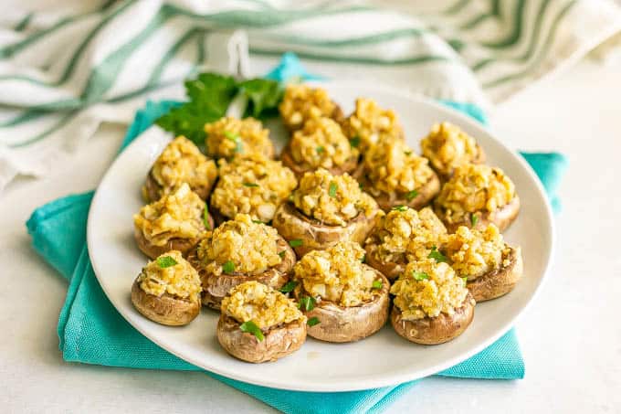 Stuffed mushrooms sprinkled with parsley and served on a white plate