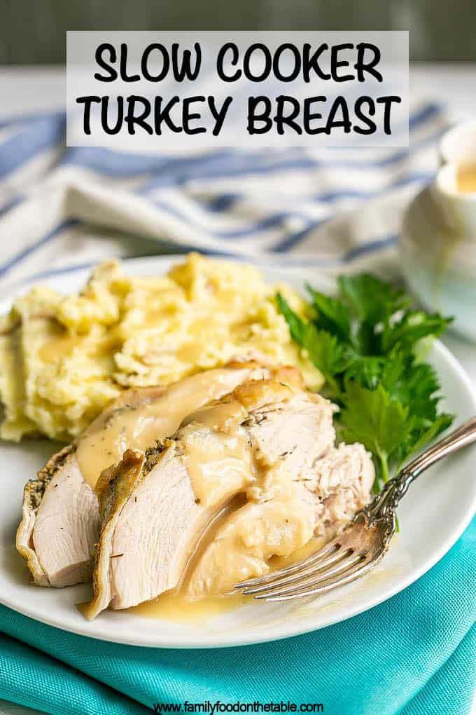 Sliced cooked turkey breast with gravy on a plate with mashed potatoes and parsley