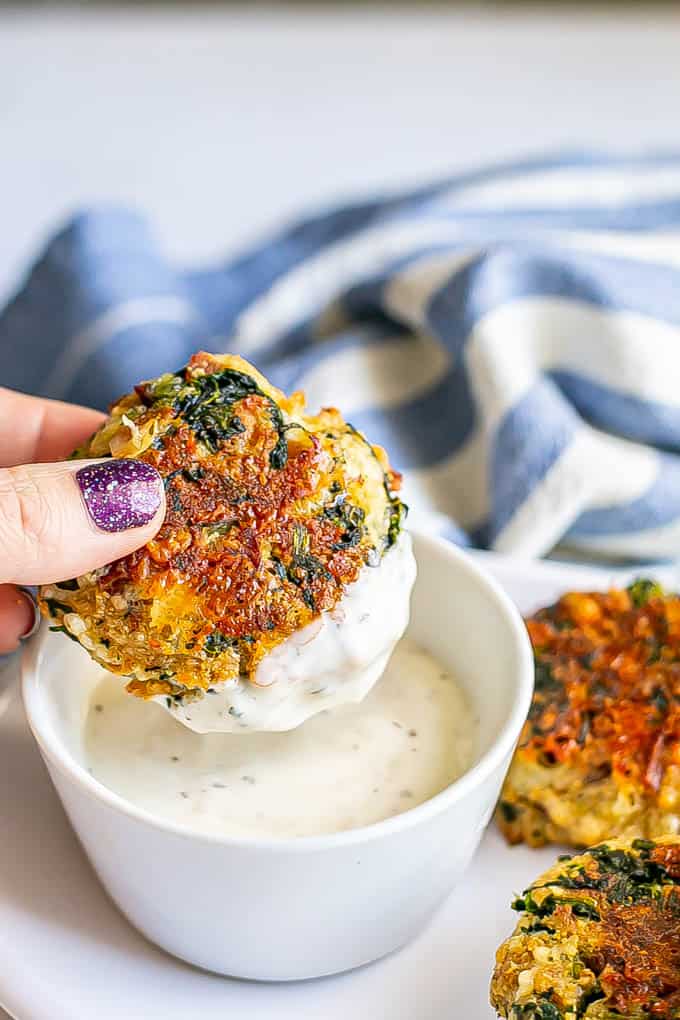 A hand holding a Ranch-dipped baked spinach cheddar bacon cake