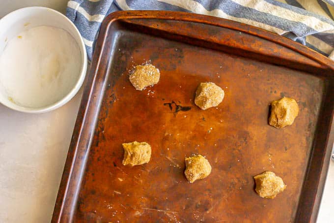 Small cookies rolled in sugar and placed on a baking sheet before baking