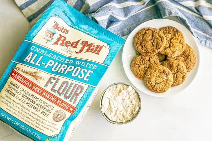 A plate of cookies next to Bob's Red Mill all purpose flour and a cup full of measured flour