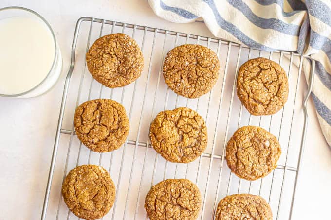 Ginger snaps on a cooling rack with a glass of milk nearby