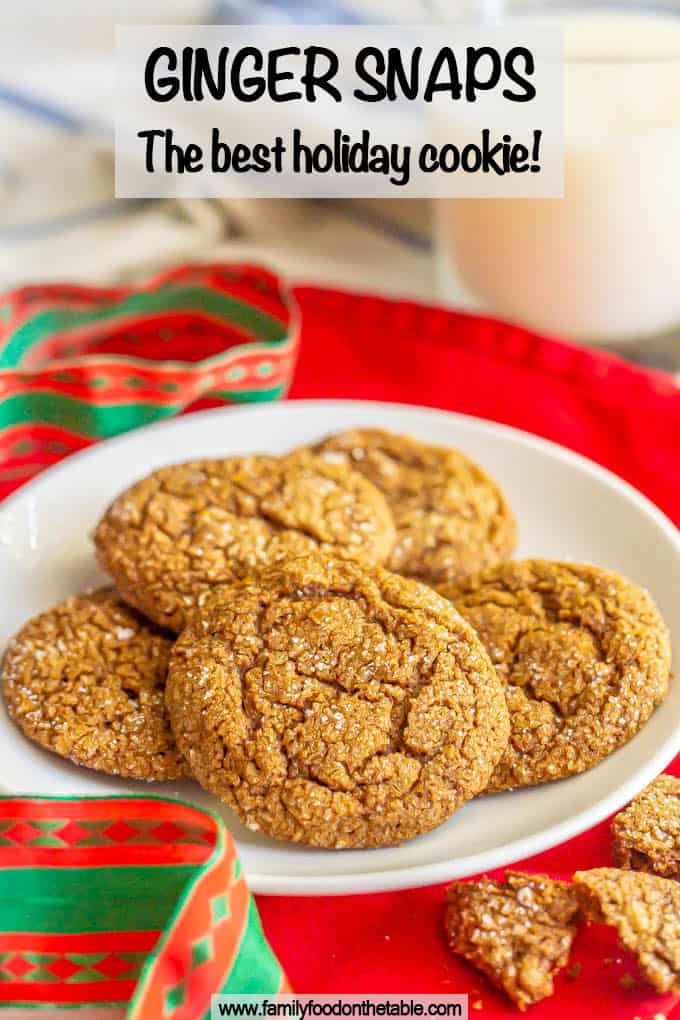 A plate of chewy ginger snap cookies with sugar on top and a Christmas ribbon nearby