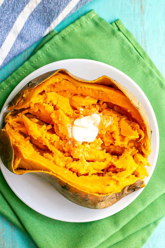 Overhead shot of an opened, cooked sweet potato with butter on top