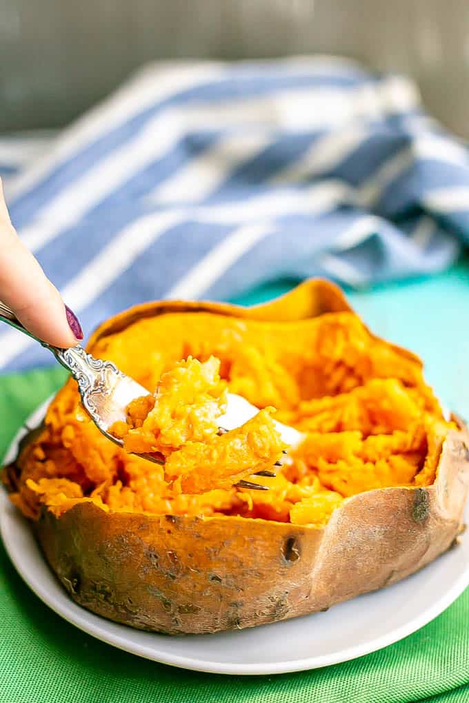 A forkful being taken from a cooked sweet potato with butter on top