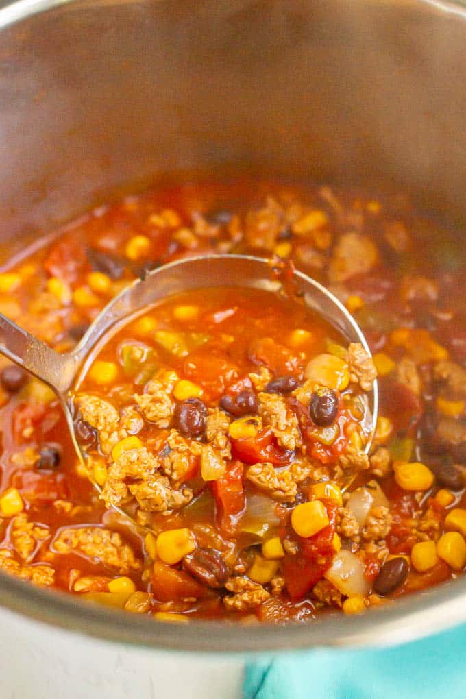 A large soup ladle scooping up some turkey chili from an Instant Pot