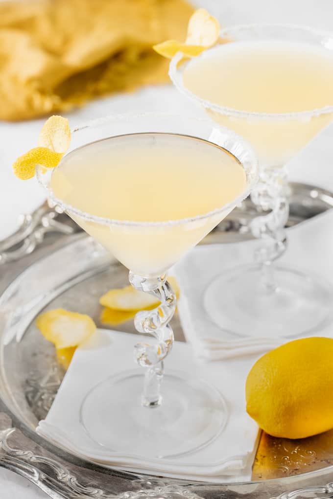 Lemon drop martinis in glasses set on white napkins in a silver serving tray