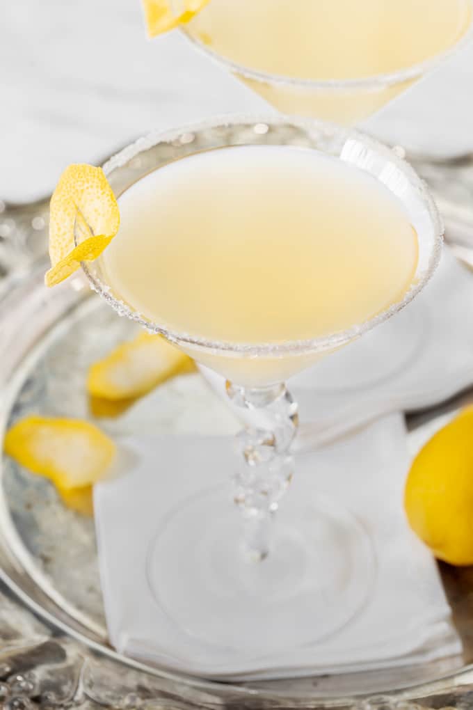 A lemon martini in a martini glass on a white napkin in a silver serving tray