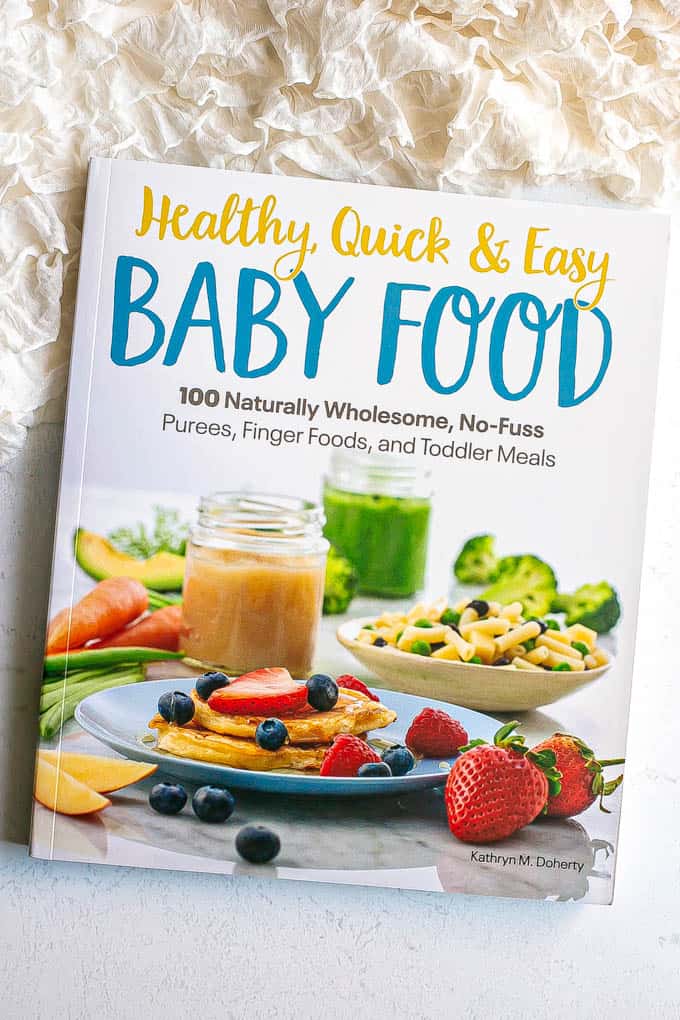 Cover of a baby food cookbook on a counter with a frilly white blanket