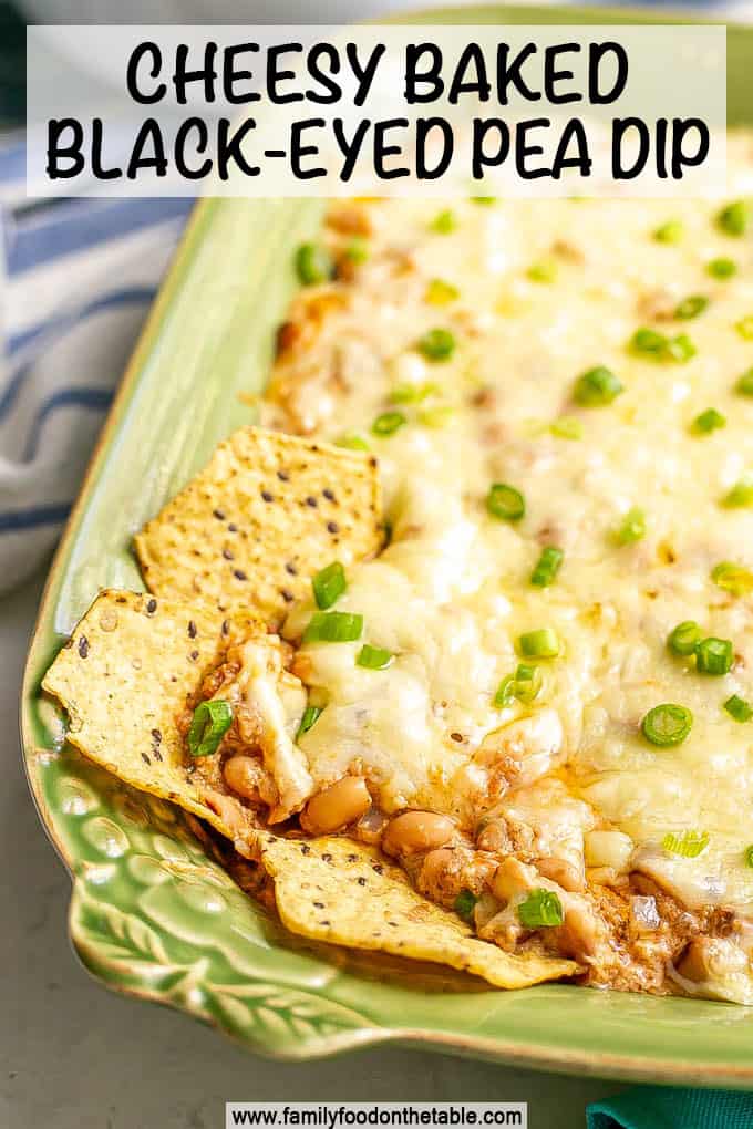 A cheesy black eyed pea dip in a casserole dish with chips dipped in and a text overlay on the photo