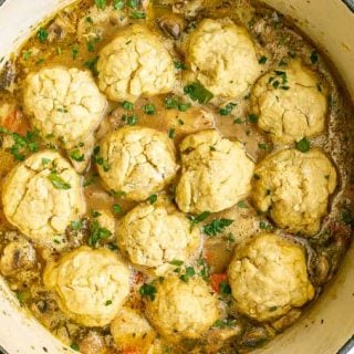 Cooked chicken and dumplings in a large purple dutch oven