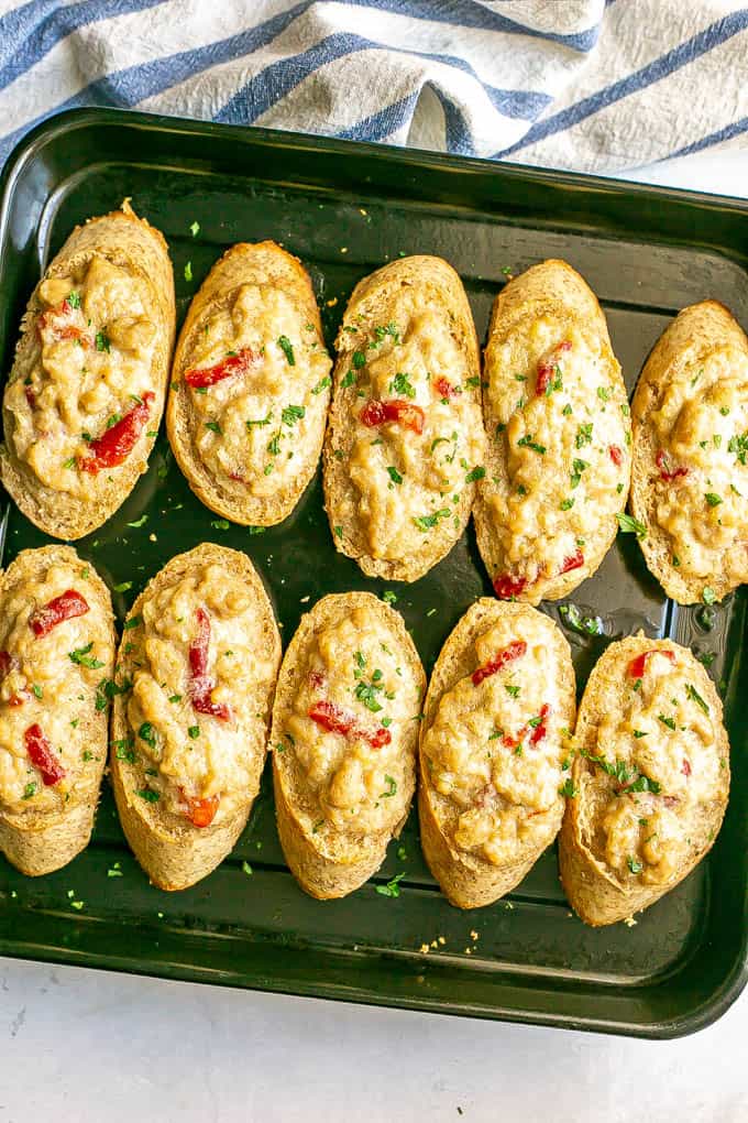 Creamy crab mixture on toasted bread pieces after coming out of the oven