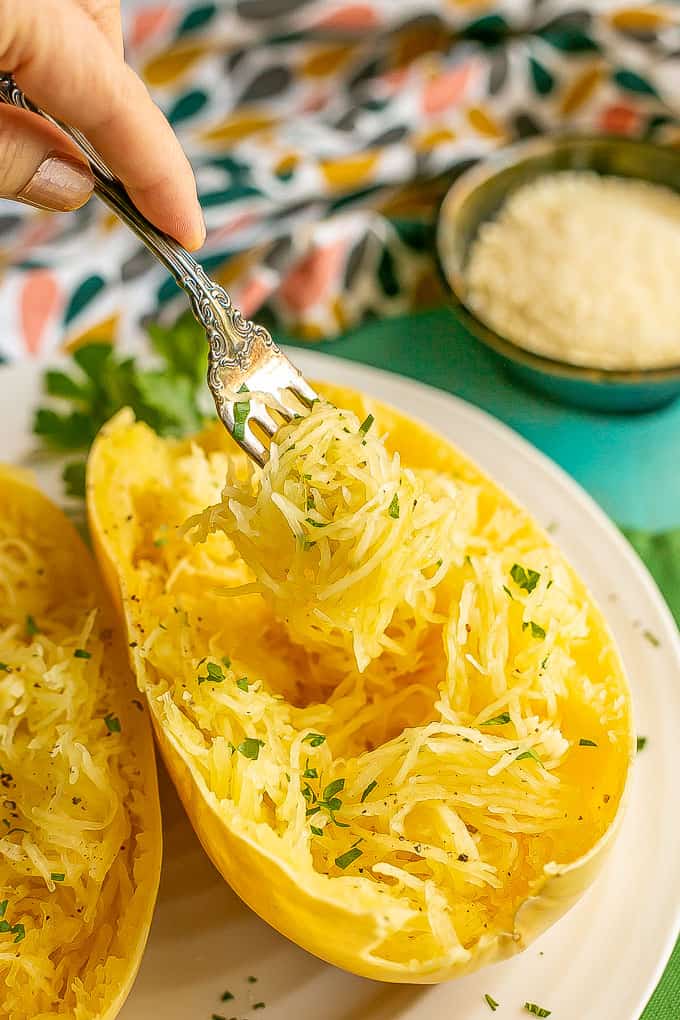 A fork lifting up some spaghetti squash strands from a spaghetti squash boat