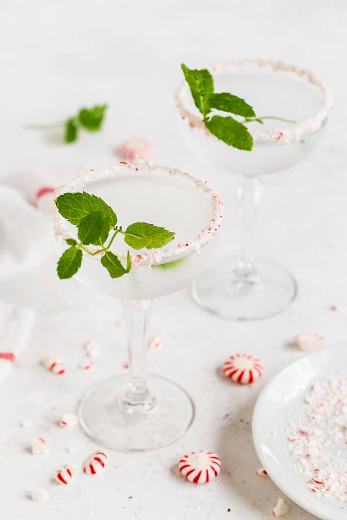 Crushed peppermint rimmed martini glasses with a clear peppermint martini and sprigs of fresh mint