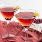 Two pomegranate martinis served in glasses with a lemon twist and a text overlay on the photo