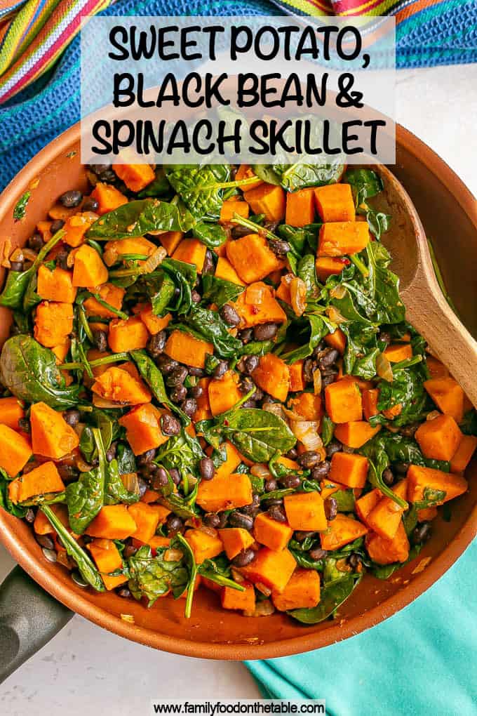 A spoon resting in a skillet of sweet potatoes with black beans and spinach with a text overlay on the photo