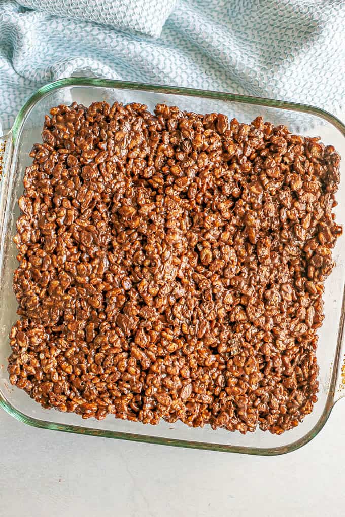 Chocolate Rice Krispies in a glass pan to cool after being mixed