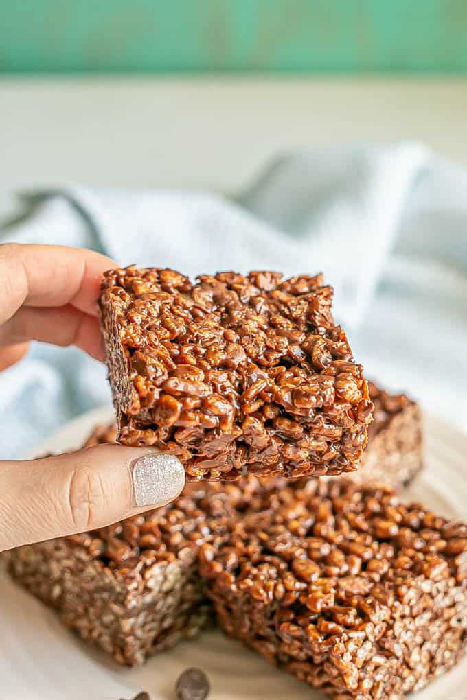 A hand picking up a thick square chocolate Rice Krispies treat