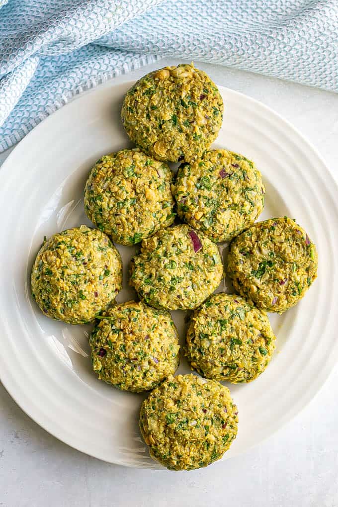 Falafel patties on a white plate before being cooked