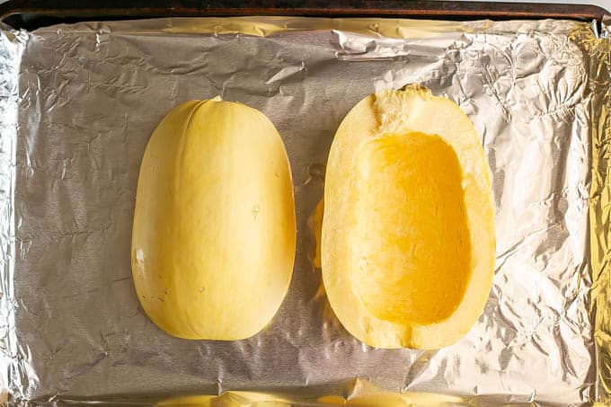 A halved spaghetti squash on a sheet pan before being baked