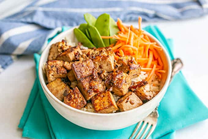 Soy marinated crispy tofu in a white bowl with rice and veggies