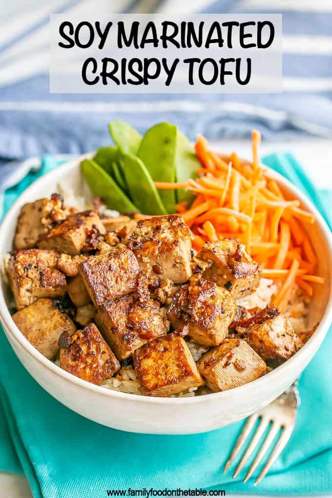 Marinated crispy tofu in a rice bowl with veggies and a text overlay on the photo