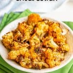 A bowl of crispy, browned, seasoned cauliflower set on some green napkins with a text overlay on the photo
