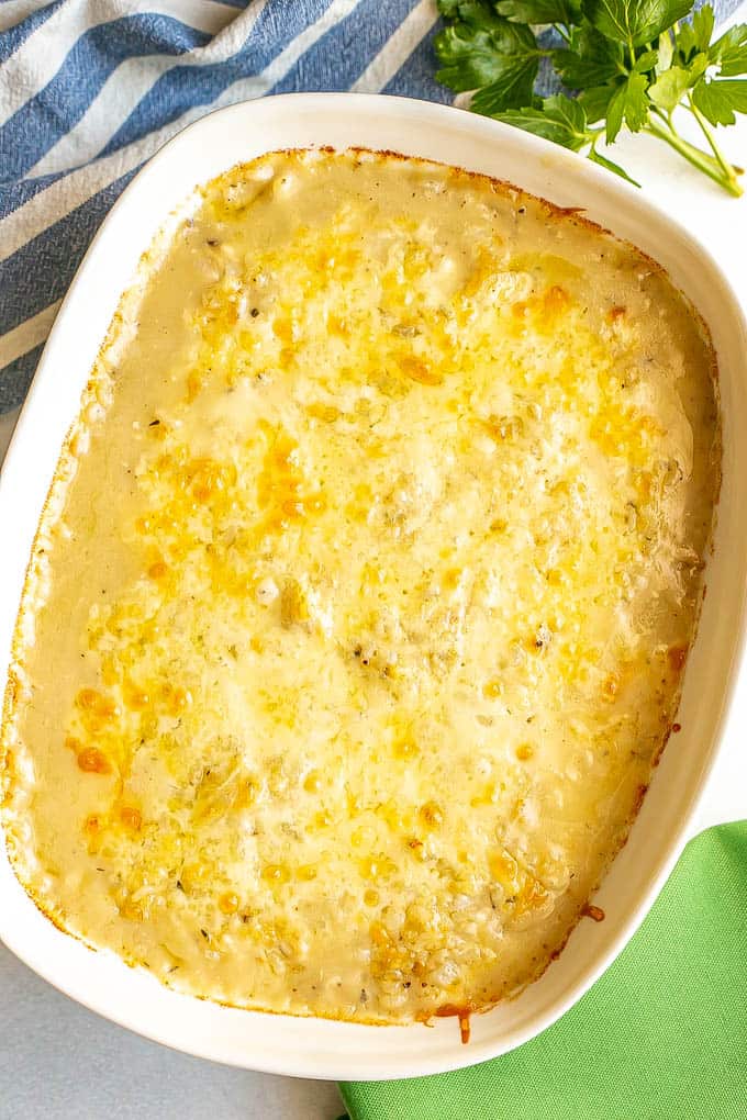 A cheese covered casserole in a white baking dish after being cooked