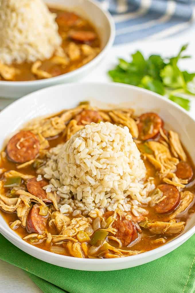 Chicken and sausage gumbo served in a wide low white bowl with a pile of rice in the middle