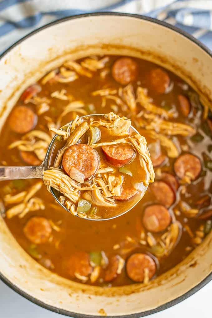 A ladle of gumbo being picked up from a large pot