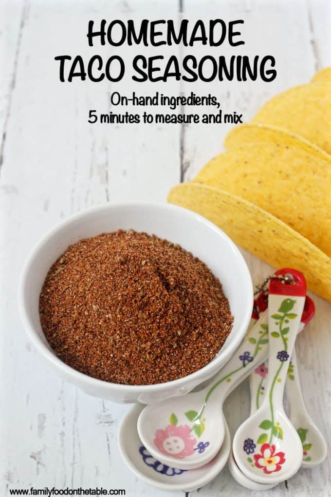 A bowl of homemade taco seasoning spice mixture with measuring spoons and taco shells nearby
