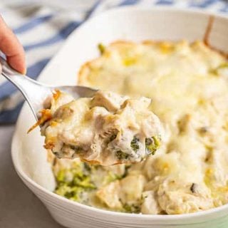 A scoop of chicken divan being lifted from a white casserole dish