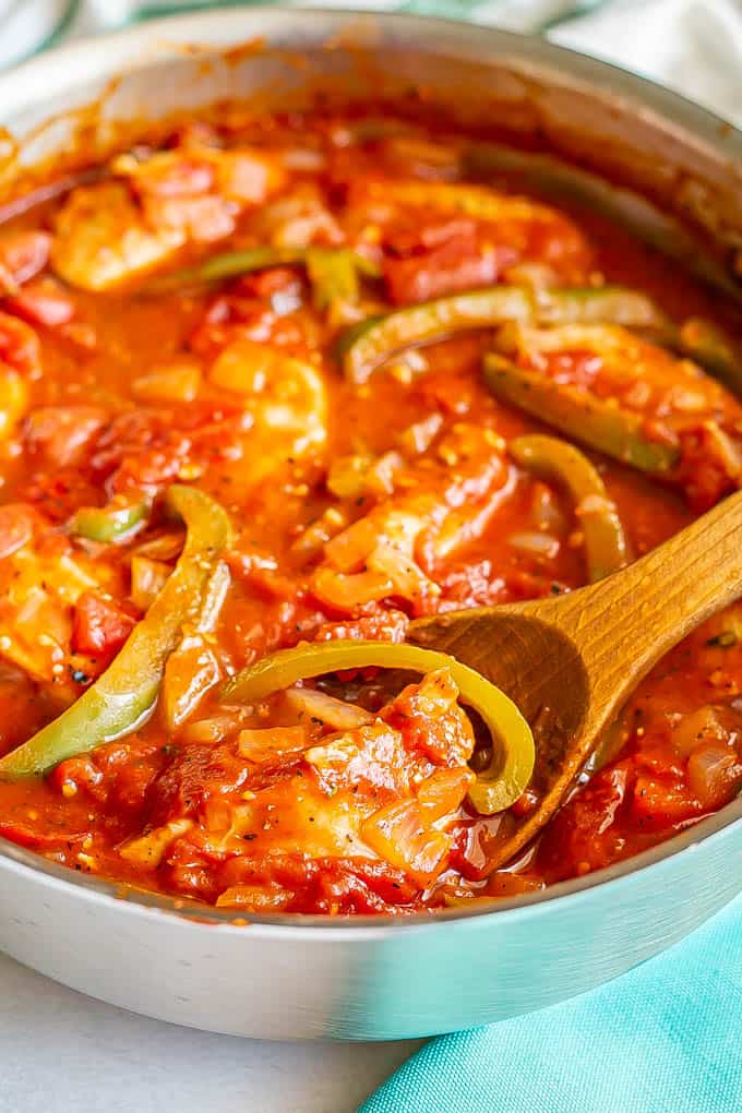 Close up of a spoonful of chicken cacciatore in a large deep skillet