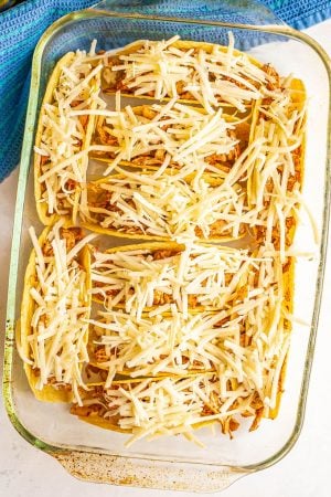 A casserole dish with chicken and cheese stuffed taco shells before being baked