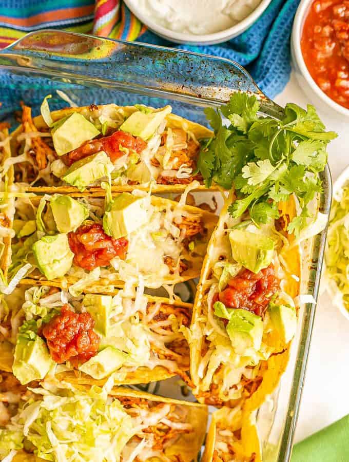 Crispy taco shells baked in a casserole dish and stuffed with shredded chicken, rice, refried beans and toppings
