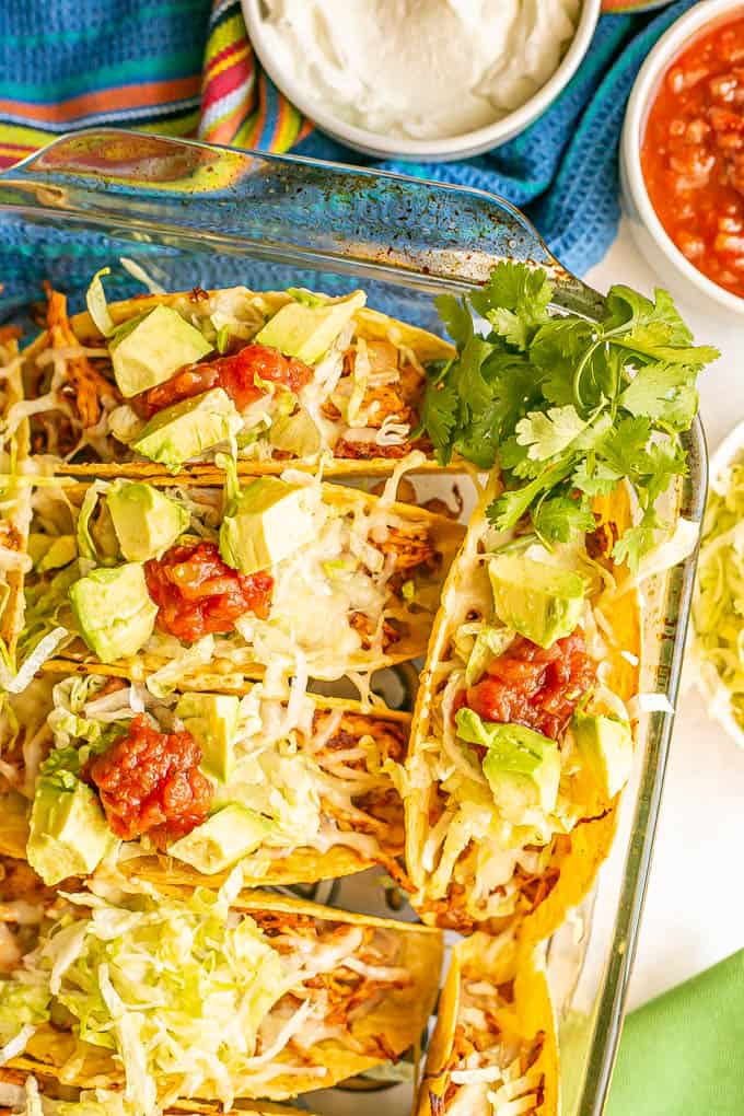 Crispy taco shells baked in a casserole dish and stuffed with shredded chicken, rice, refried beans and toppings