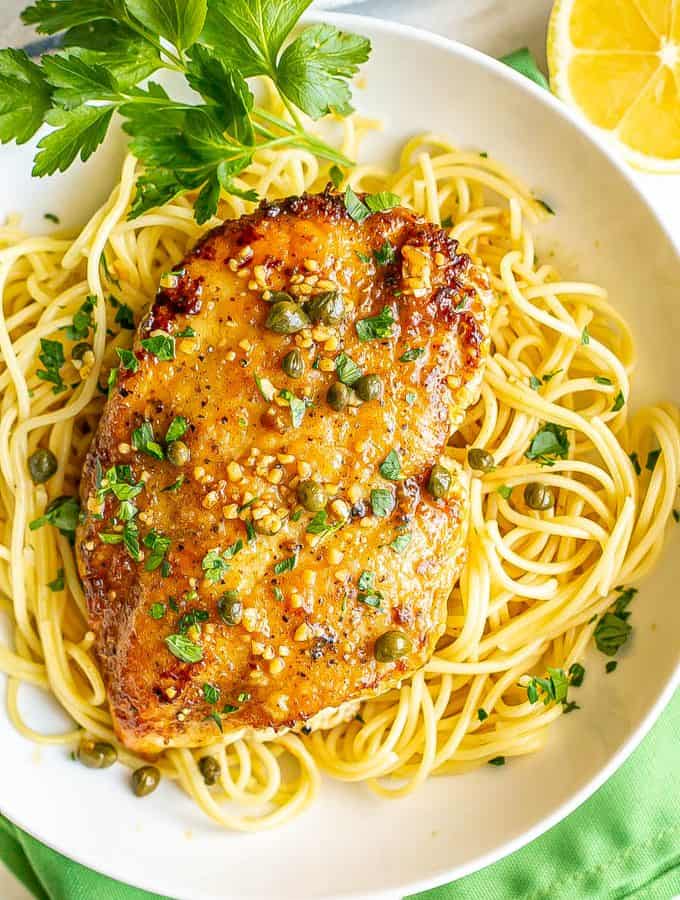 A thin, browned chicken breast served over spaghetti noodles with a sauce of capers, lemon and white wine